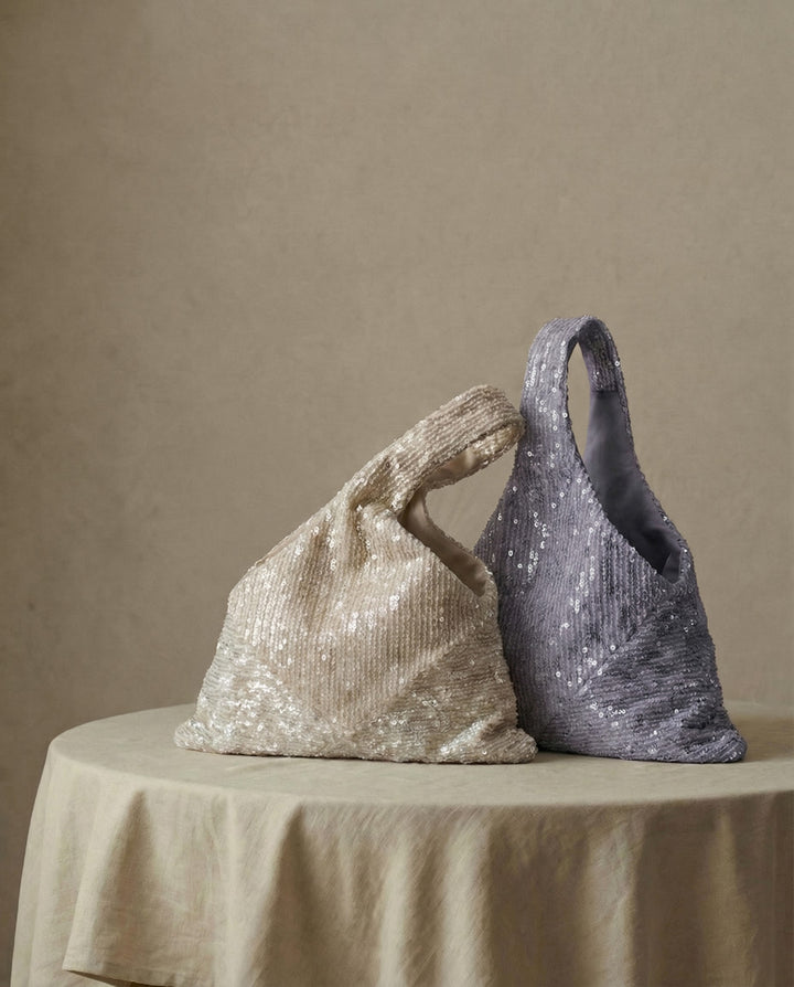 Champagne and lavender sequin purses displayed side by side