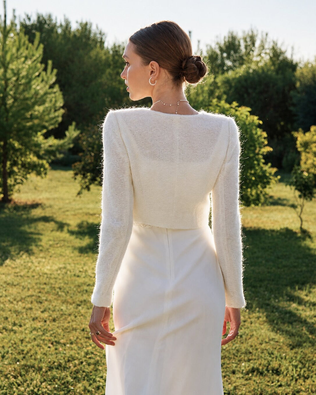 Back view of a bride wearing an ivory knit wedding dress topper