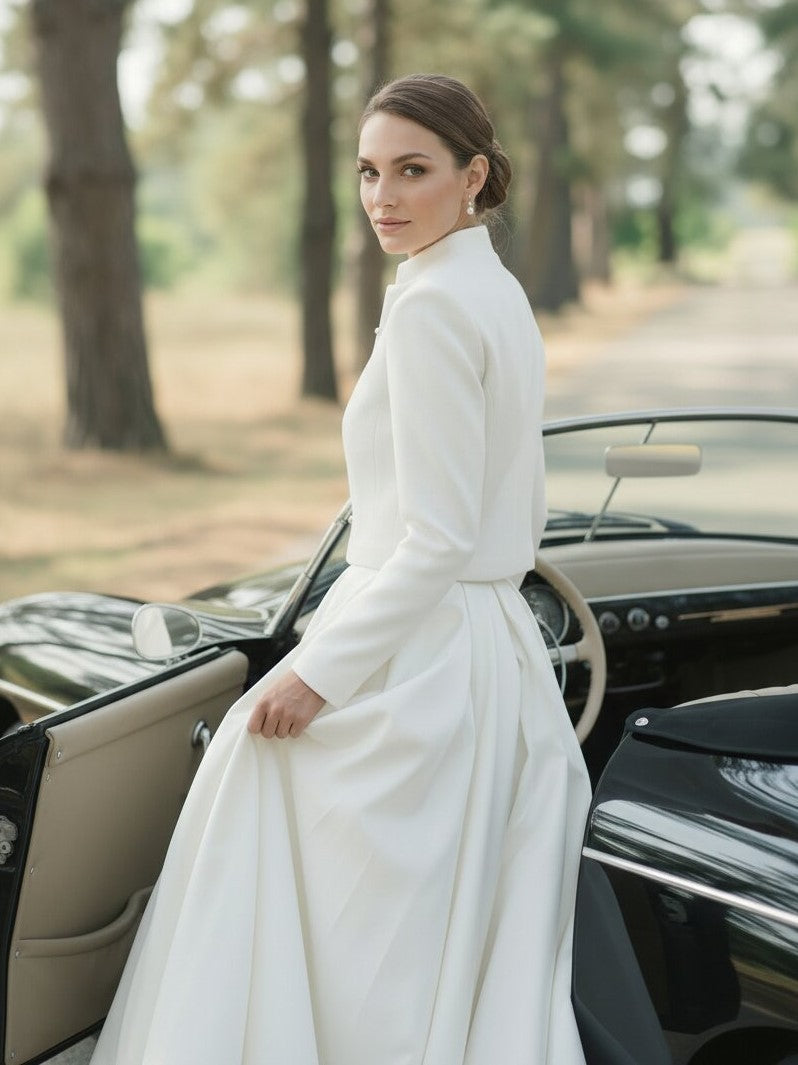 Bride wearing an ivory wedding bolero with long sleeves beside a vintage car
