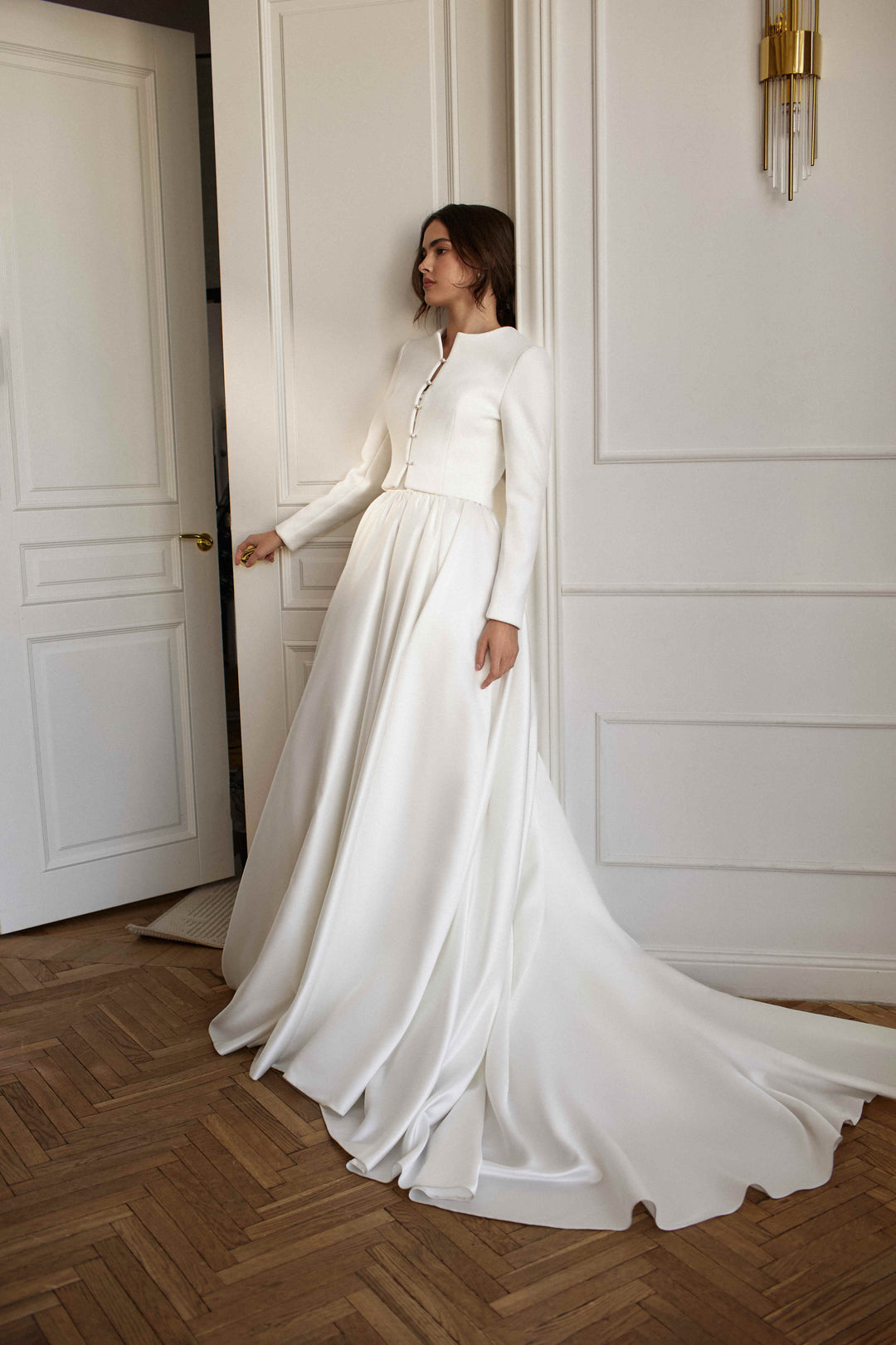 A bride wearing an ivory wedding cover-up with a flowing gown in a classic interior