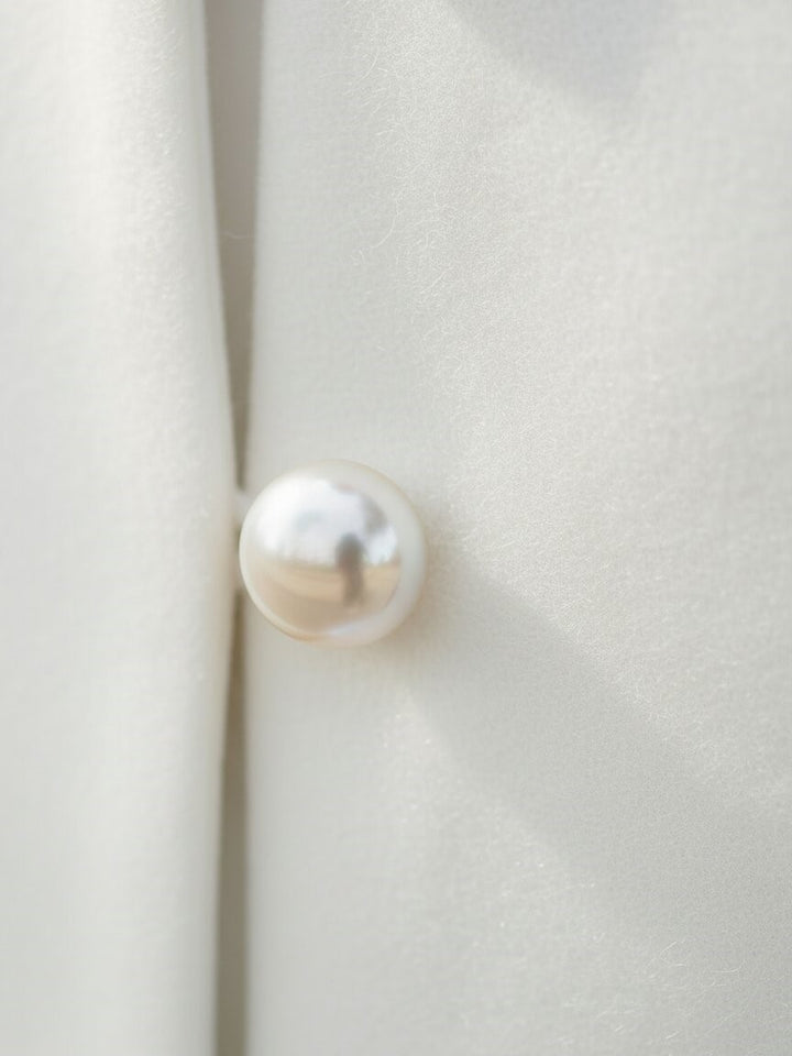 Close-up of a pearl-style button on an ivory bridal jacket