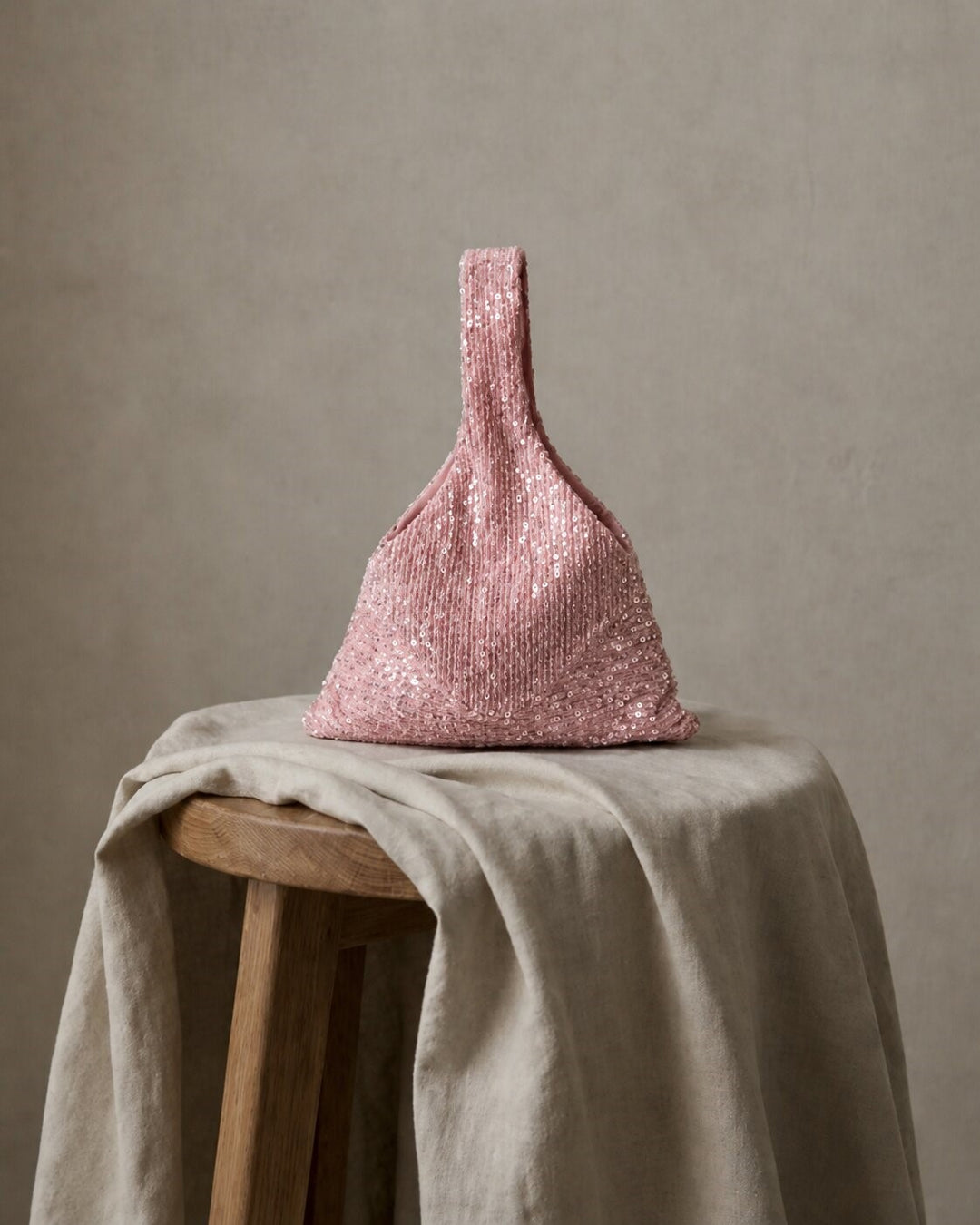 Pink sequin bridal handbag displayed on a draped table