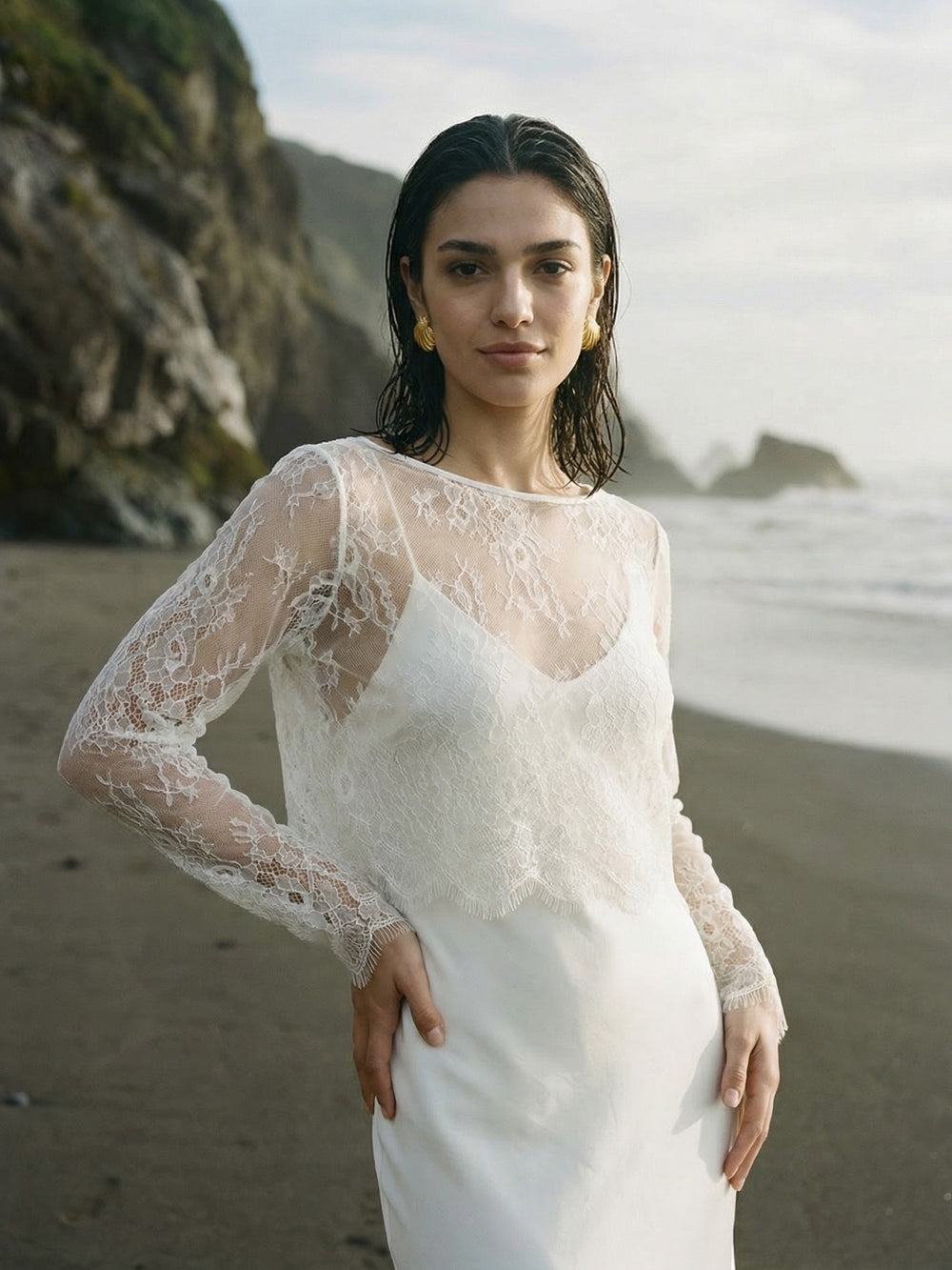 Woman wearing a delicate lace bridal top with long sleeves and a white gown