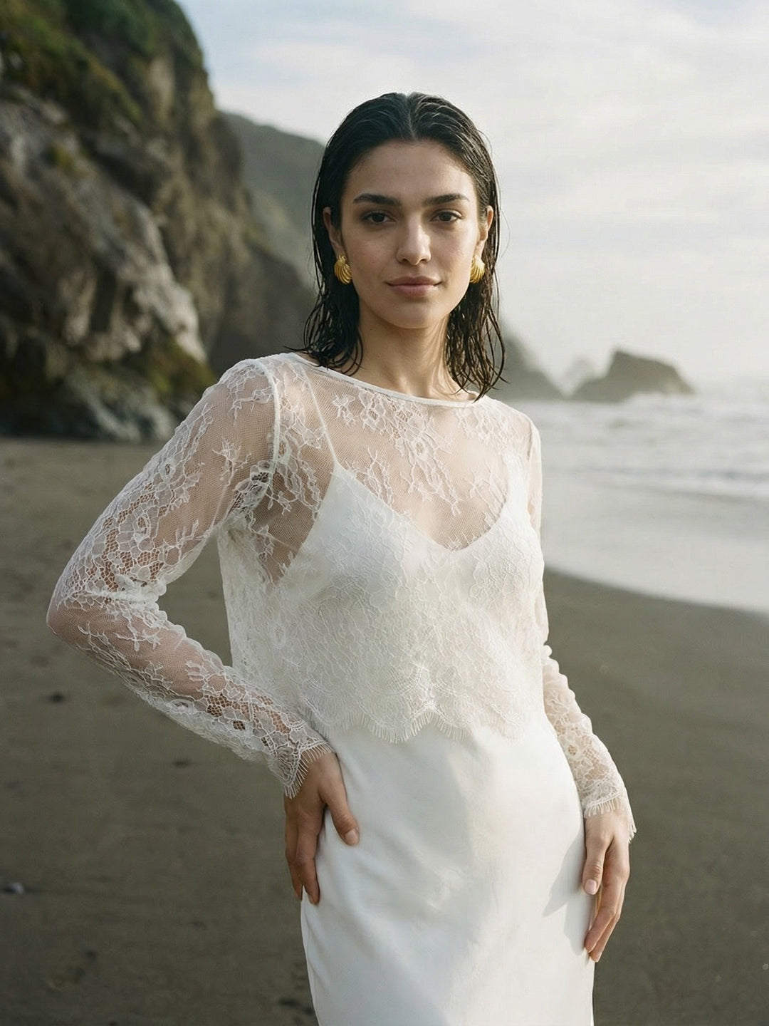 Woman wearing a delicate lace bridal top with long sleeves and a white gown