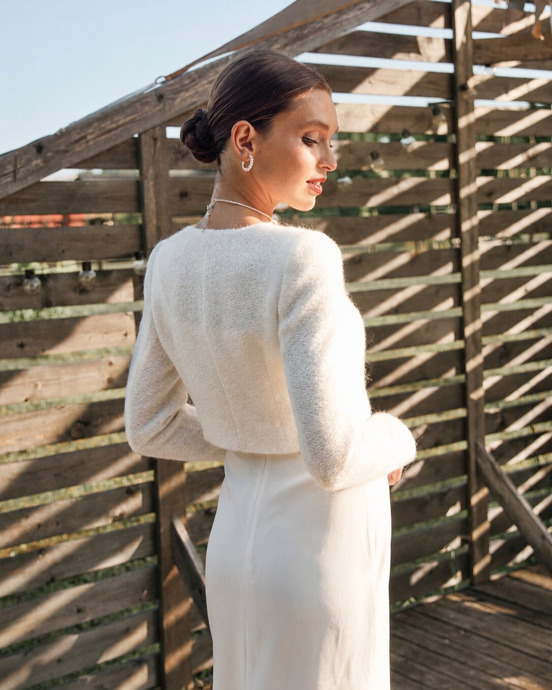 Woman wearing a white knitted wedding cardigan with a cropped silhouette